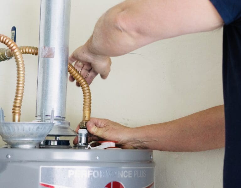 Man working on repairing the pipe on a hot water heater